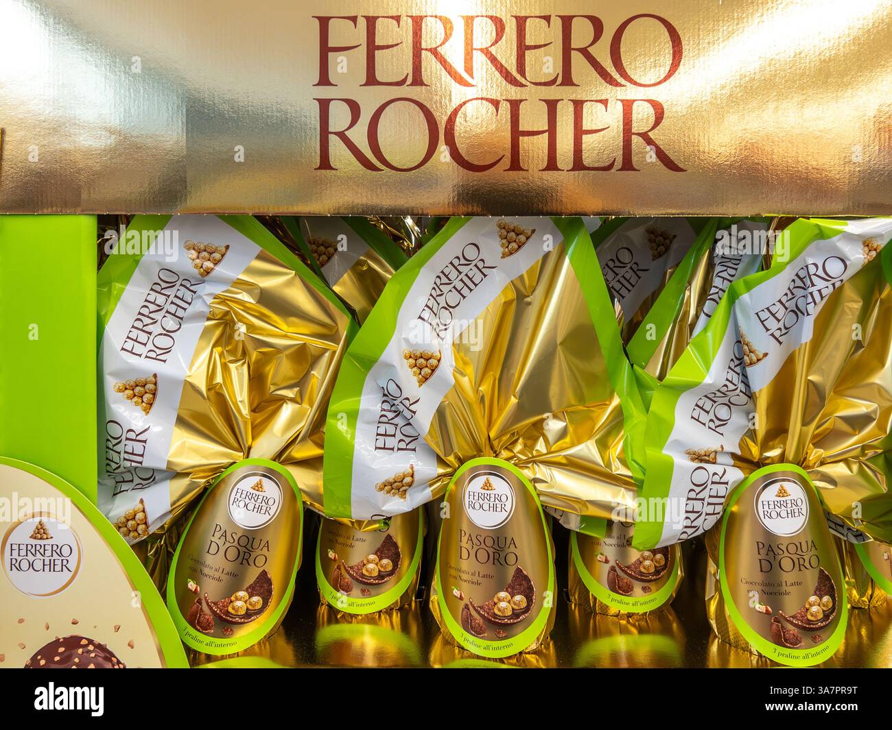 Italia - 25 marzo 2025: Uova di cioccolato pasquale Ferrero Rocher con cioccolatini rocker a sorpresa in esposizione in cartone dorato in vendita in supermar italiano Foto Stock