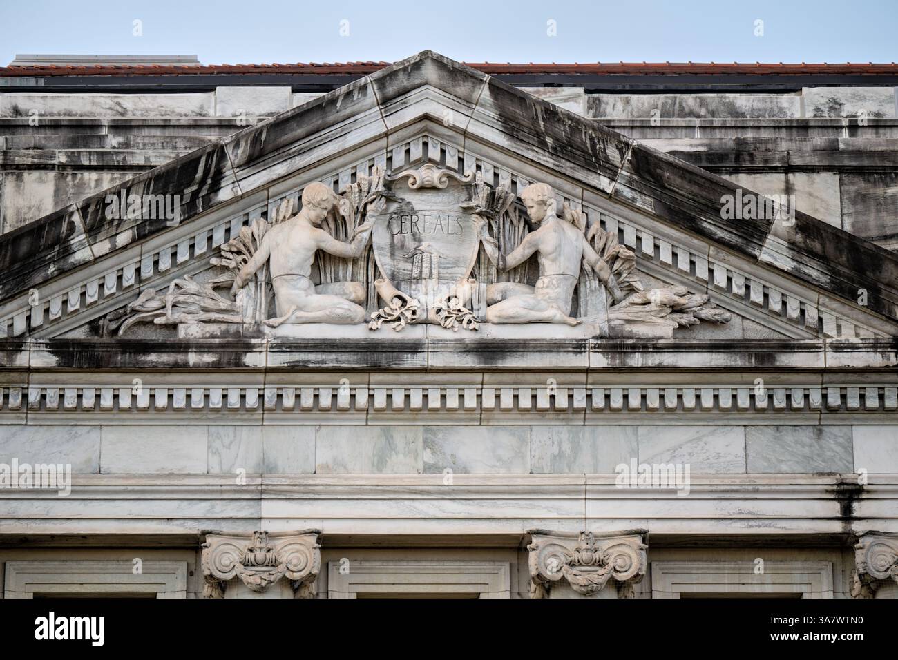 US Department of Agriculture Building a Washington DC | WASHINGTON D.C., Stati Uniti - Un frontone in pietra calcarea scolpita sul quartier generale del Dipartimento dell'Agricoltura degli Stati Uniti raffigura figure allegoriche che fiancheggiano uno scudo inciso "cereali", incorniciato da pulegge di frumento e mais. L'edificio Beaux-Arts, completato nel 1930 e conosciuto oggi come Jamie L. Whitten Federal Building, si trova lungo Independence Avenue vicino al National Mall. La sua facciata porta diversi rilievi che celebrano i prodotti agricoli americani. Foto Stock