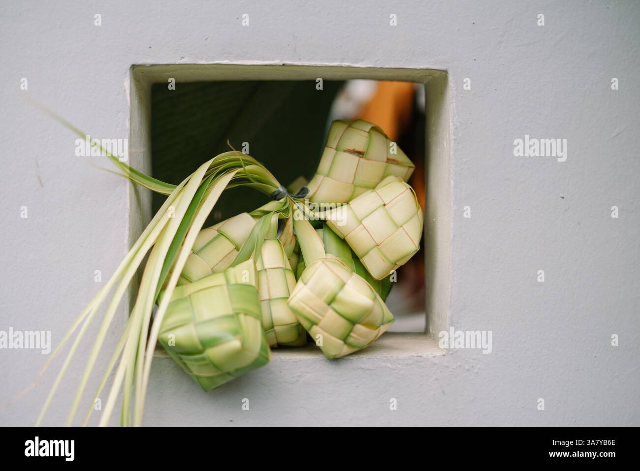 Primo piano di ketupat, un tradizionale gnocco di riso del sud-est asiatico, appeso su una finestra durante la celebrazione di Eid al-Fitr. A forma di diamante Foto Stock