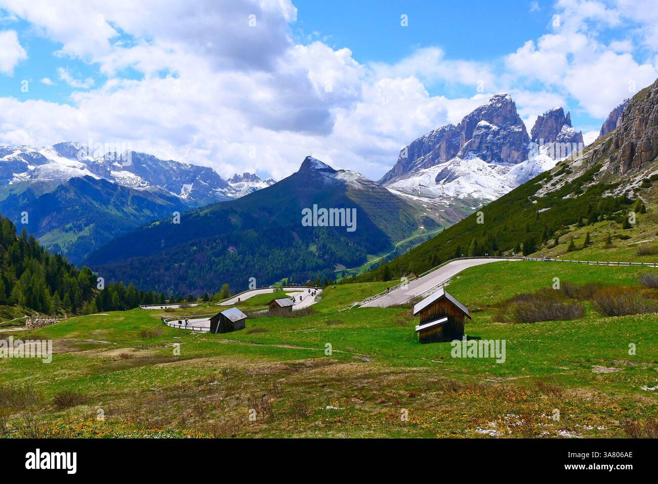Una vista panoramica dal passo Pordoi nelle Dolomiti delle montagne innevate, dei piccoli bastoncini di legno e di una strada a serpentina Foto Stock