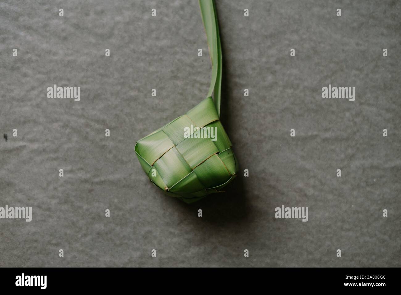 Ketupat è una torta di riso a forma di diamante avvolta da giovani foglie di cocco intrecciate, è una specialità culinaria del sud-est asiatico. Servita durante le festività Foto Stock