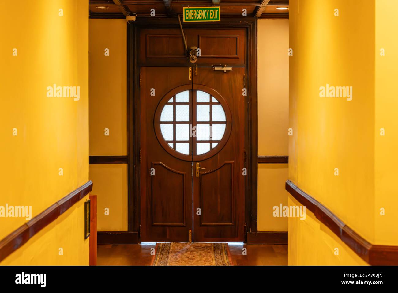 Nuwara Eliya Sri Lanka - 5 settembre 2024; segnale di uscita di emergenza interno caratteristica architettonica finestra circolare in doppie porte a battente alla fine del corridoio Foto Stock