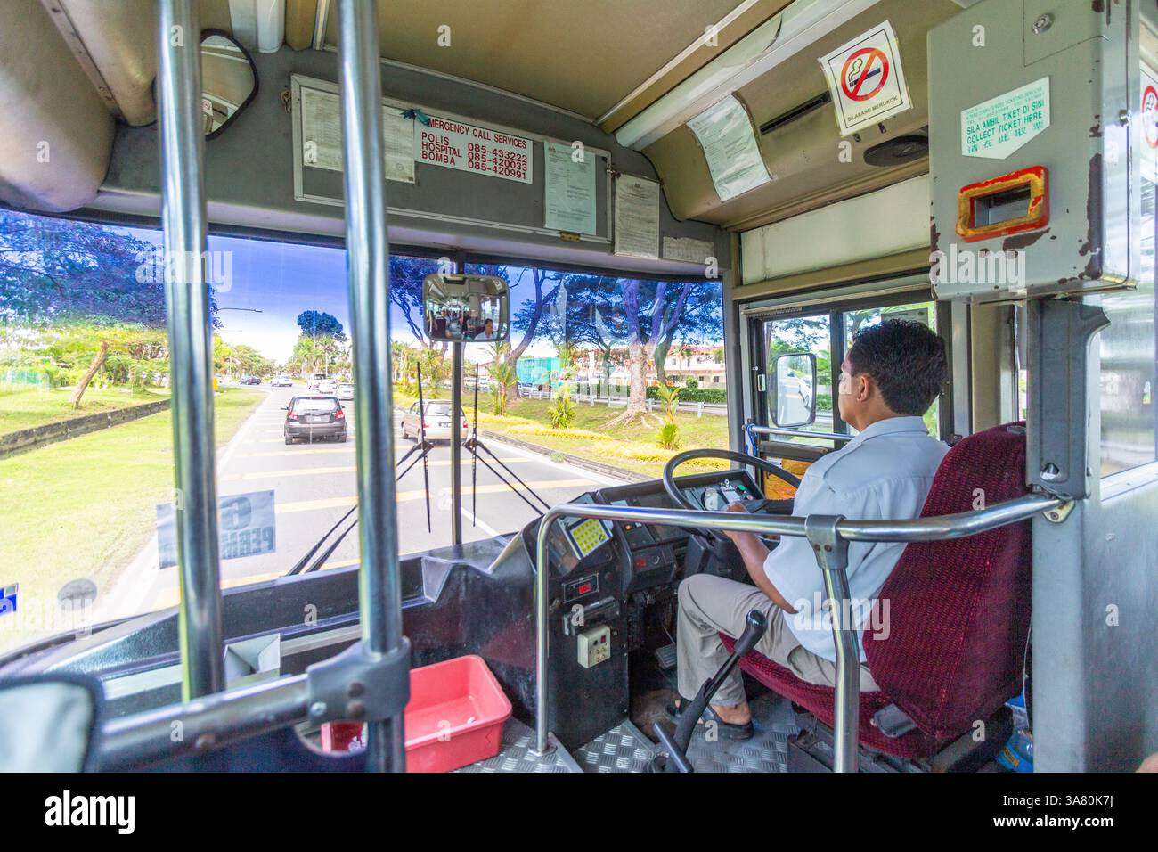 Un autista di autobus che guida il suo autobus su una strada a Miri Sarawak in Malesia Foto Stock