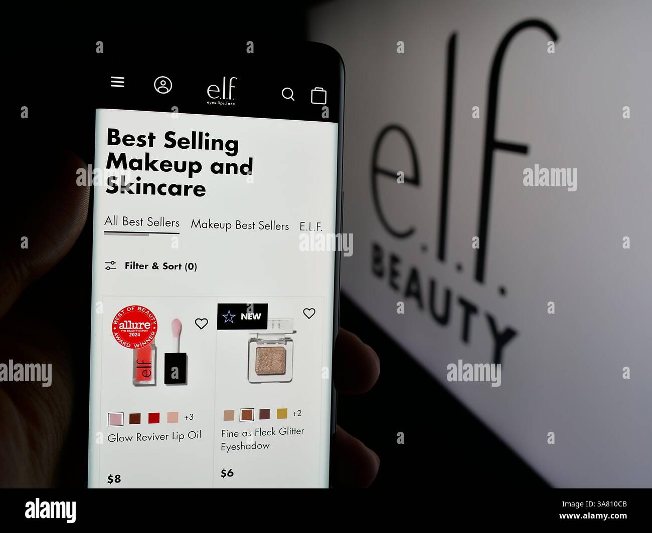 In questa illustrazione fotografica, una persona ha in mano un cellulare con la pagina web della società di cosmetici statunitense, e.l.f. Beauty Inc. Sullo schermo davanti al logo. Foto Stock