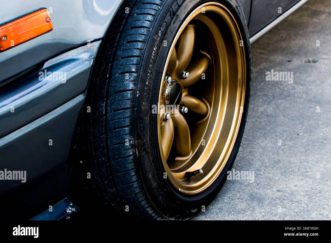 Primo piano del cerchio in lega d'oro con pneumatico, Automotive Concept Foto Stock