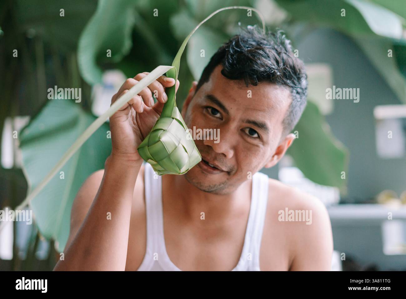 Un ritratto cattura un uomo che tiene "ketupat", un tradizionale gnocco di riso, durante la celebrazione di Eid al-Fitr. Simboleggia il patrimonio culturale e il festival Foto Stock