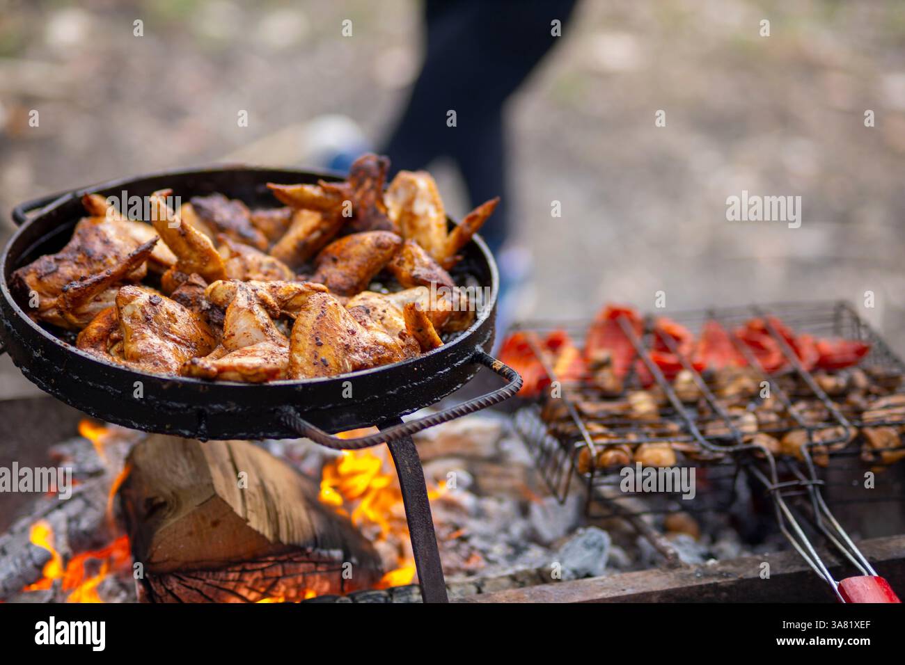 Grigliare ali di pollo e verdure sul fuoco Foto Stock