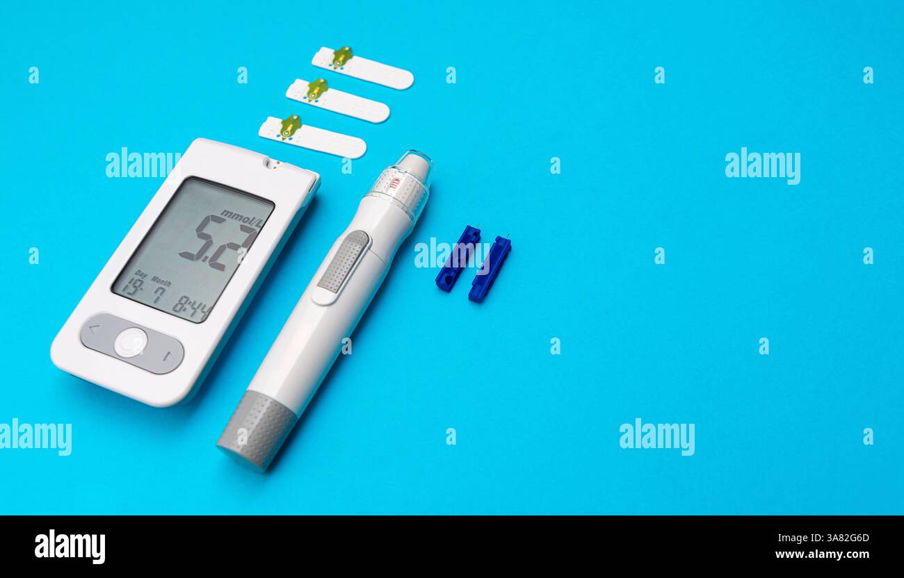 Glucometro ematico e penna per insulina posizionati su sfondo blu con strisce reattive e lancette organizzate accanto per la gestione del diabete. Foto Stock