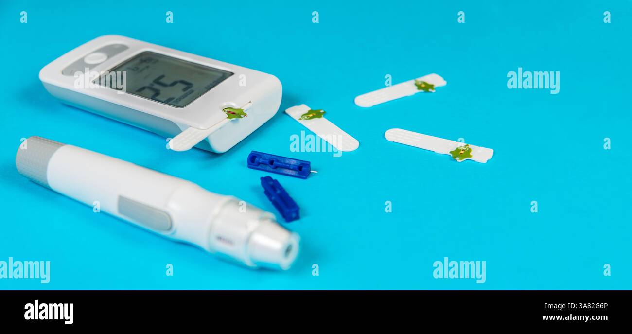 Glucometro ematico e penna per insulina posizionati su sfondo blu con strisce reattive e lancette organizzate accanto per la gestione del diabete. Foto Stock