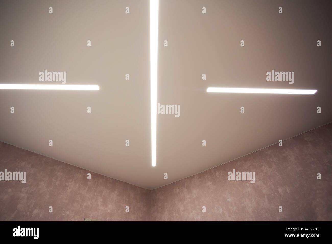 Soffitto allungato di design moderno con linee LED illuminate in camera. Foto Stock