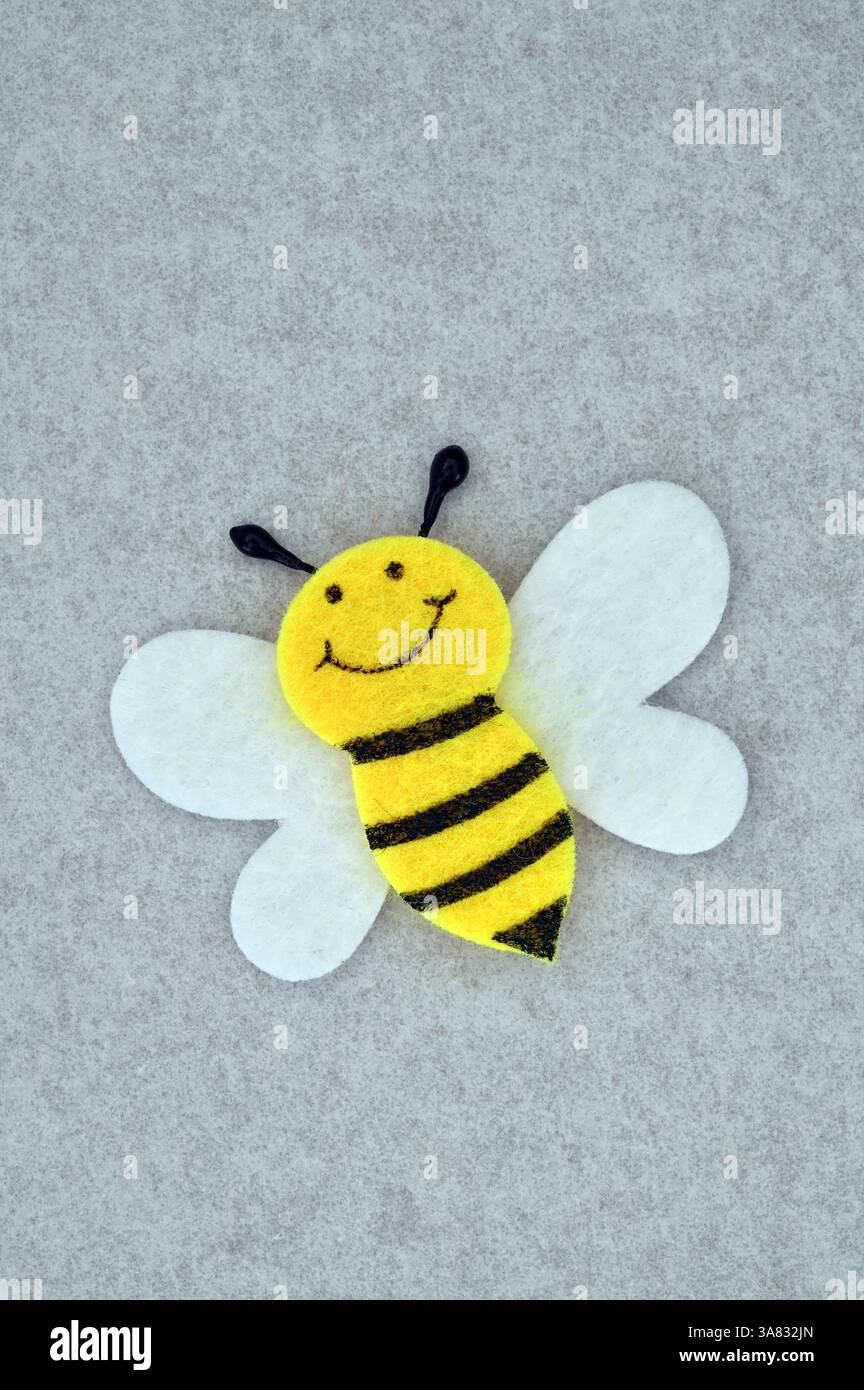 Modello in feltro di Bee con faccia sobria e audaci strisce nere e gialle Foto Stock