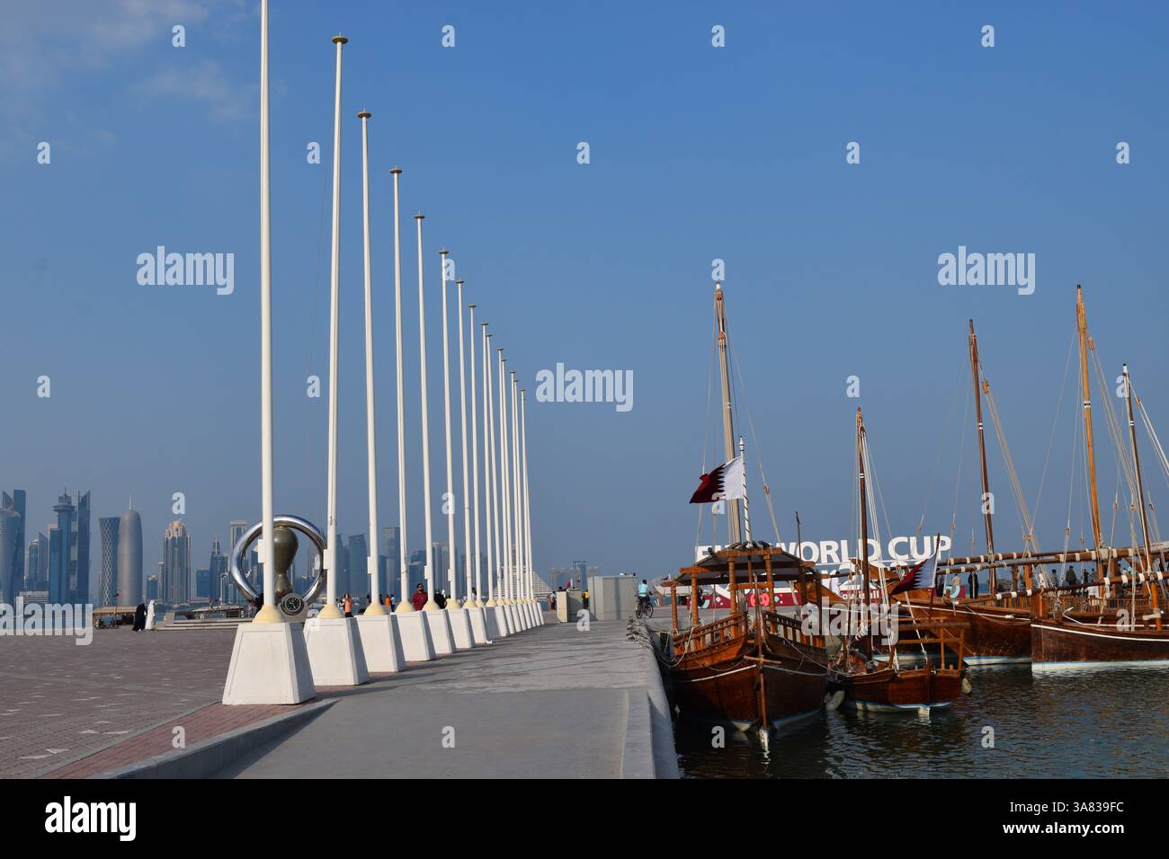 Fusione culturale del Qatar: I tradizionali dhow in legno adornati con insegne per la Coppa del mondo attraccano accanto a un moderno lungomare di Doha Foto Stock