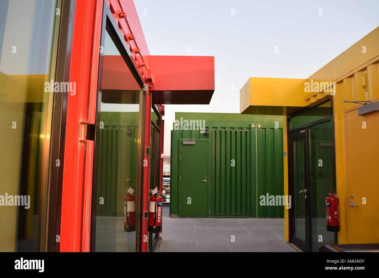 Un vivace vicolo di container riutilizzati trasformati in spazi moderni, dove l'architettura incontra il colore e la creatività Foto Stock