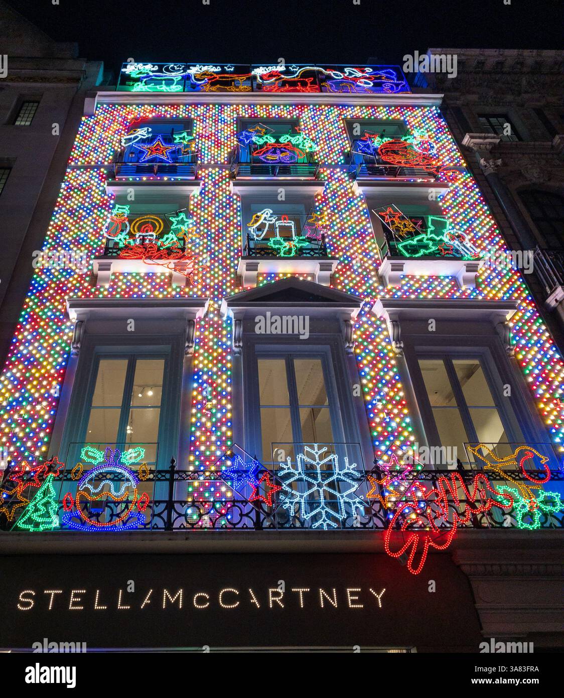 Il negozio Stella McCartney di Londra, illuminato da vivaci luci colorate per Natale, crea un'esposizione festosa e accattivante di notte. REGNO UNITO Foto Stock