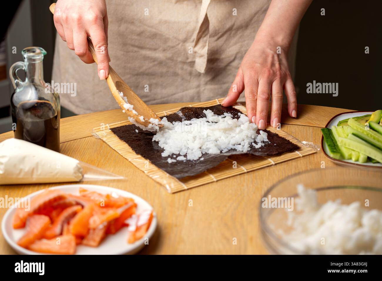Preparare sushi a casa. Aggiungere riso su nori. Foto Stock
