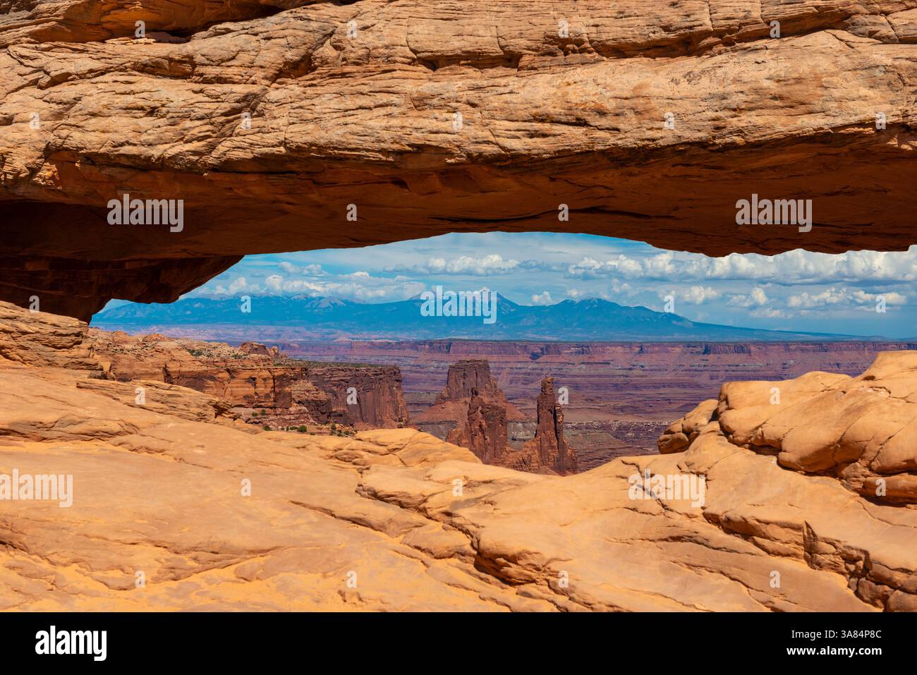 Mesa Arch con il paesaggio profondo delle Montagne Rocciose, il parco nazionale di Canyonlands, Utah, Stati Uniti. Foto Stock