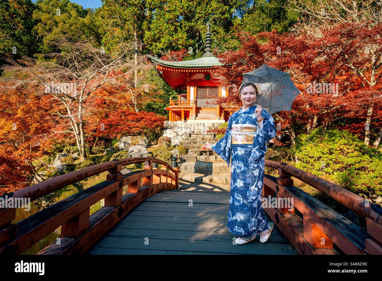 Donna giapponese che posa nell'iconico tempio Diago-ji di Kyoto con colori autunnali. Ponte con sentiero per il tempio giapponese Foto Stock
