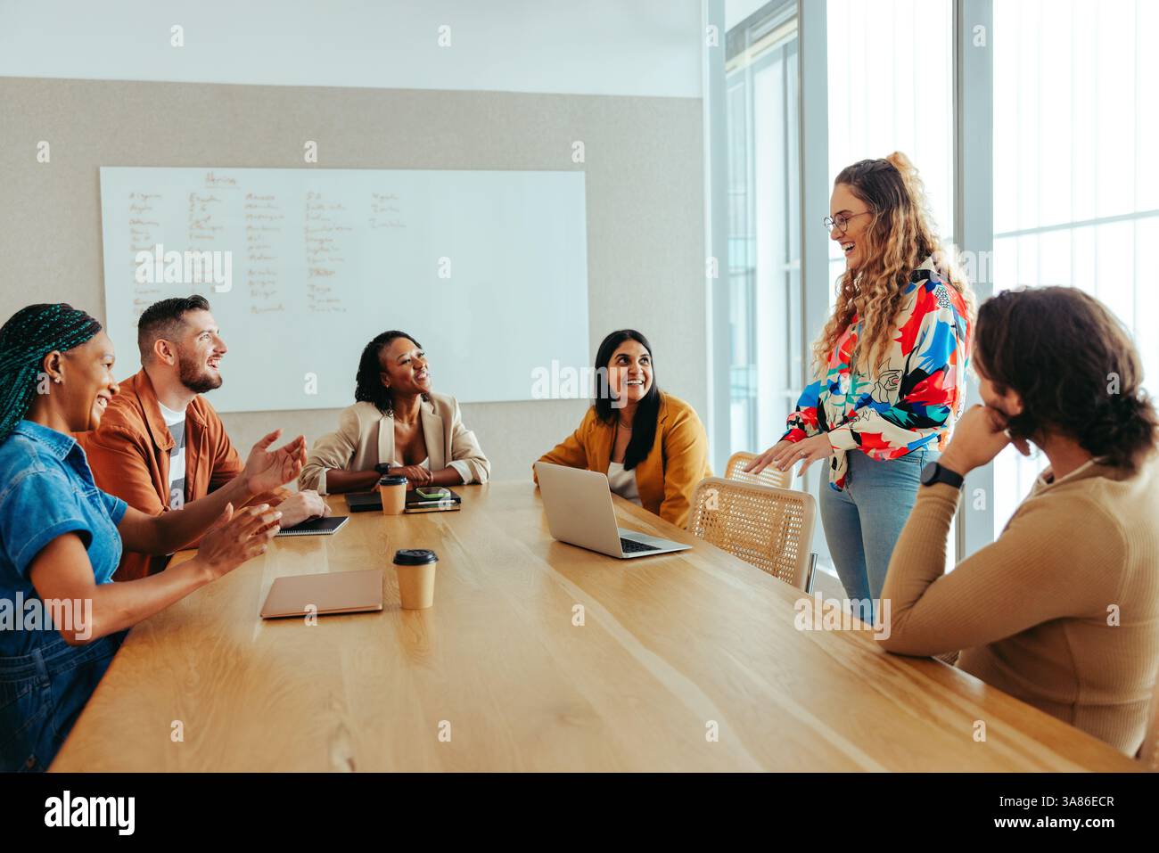 Un gruppo diversificato di professionisti del marketing digitale impegnati in una riunione. Il team sta discutendo strategie e idee in un ambiente aperto. Foto Stock