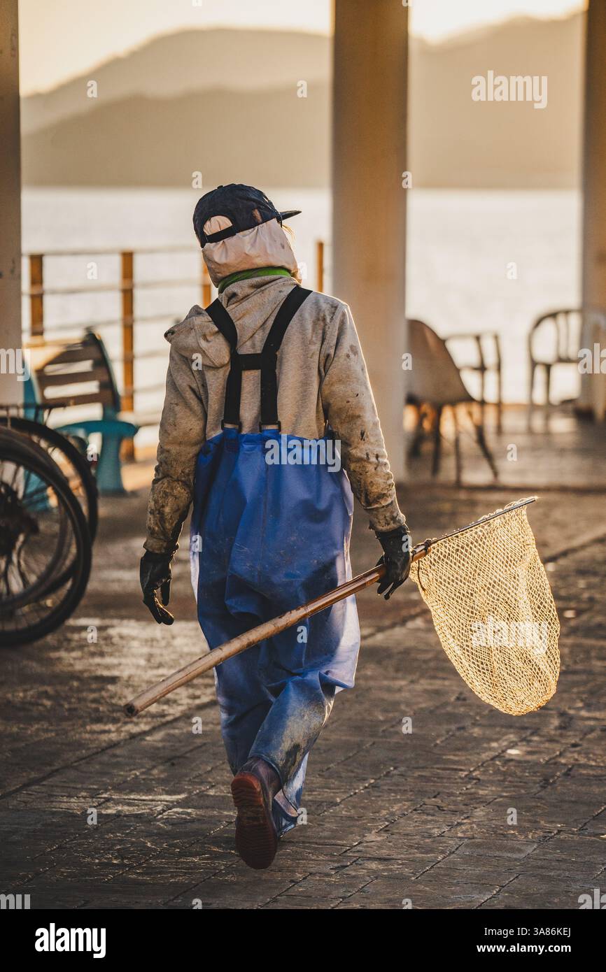Una pescatrice a Peng Chau a Hong Kong con una rete al tramonto, Hong Kong, Cina Foto Stock