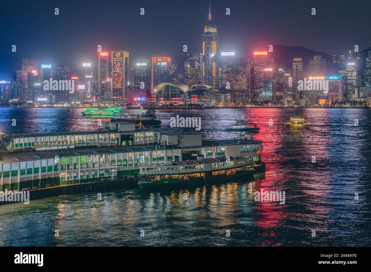 Lo skyline di Hong Kong di notte con il terminal Star Ferry in primo piano, Hong Kong, Cina Foto Stock