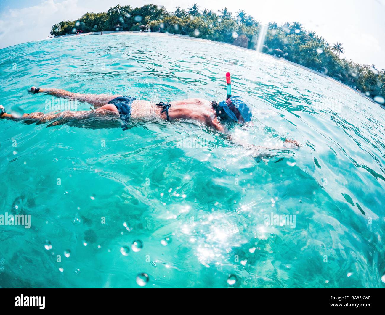 Donna che fa snorkeling nel mare tropicale cristallino, nelle Maldive, nell'Oceano Indiano Foto Stock