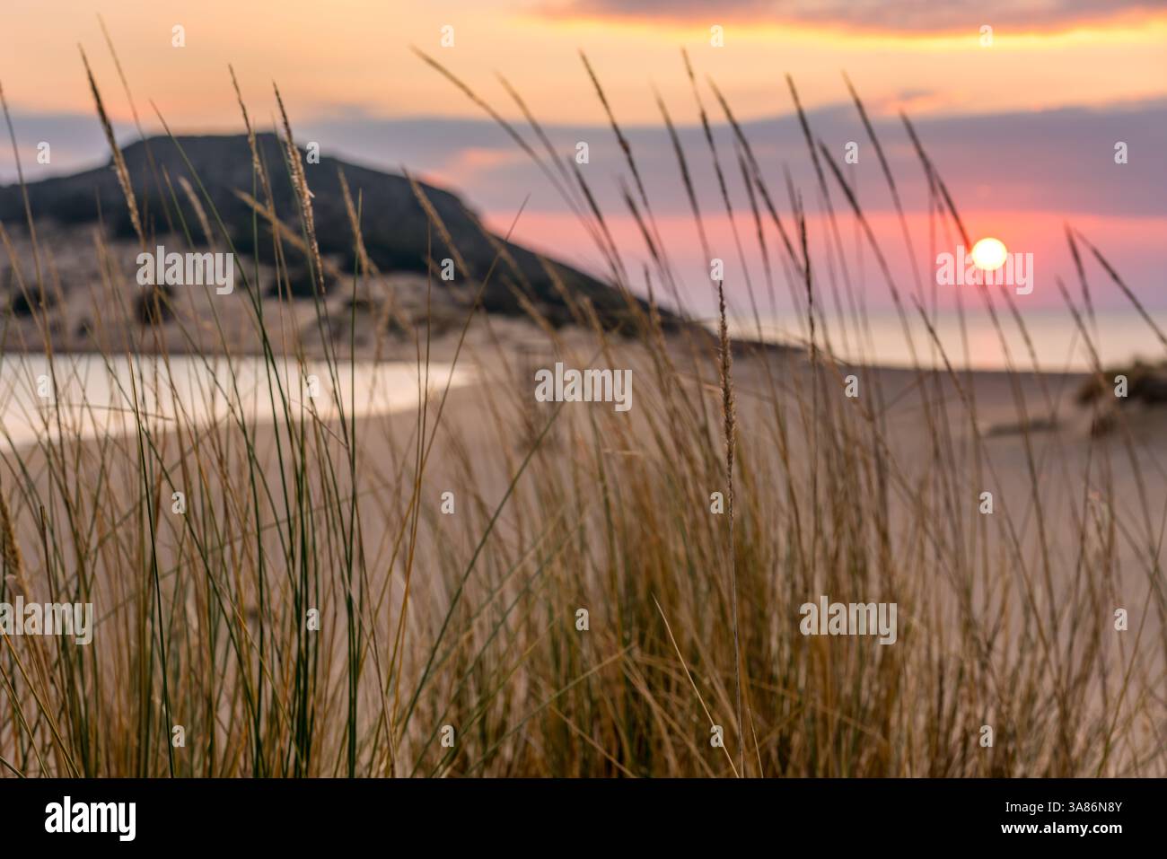 Il sole tramonta in mare su una spiaggia naturale selvaggia, l'isola di Elafonisos, Grecia Foto Stock