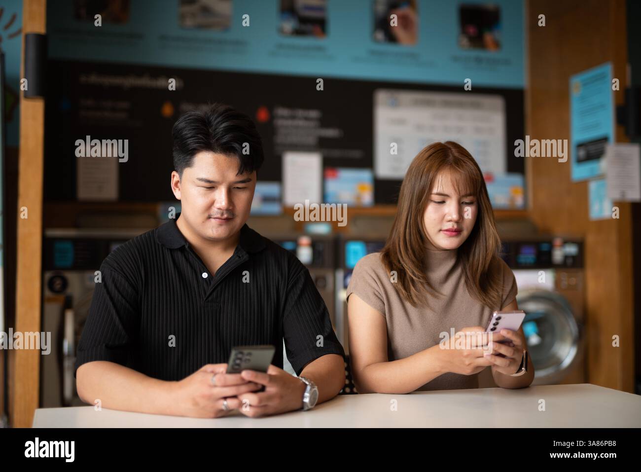 Giovane coppia asiatica fiduciosa nel negozio di lavanderia Foto Stock