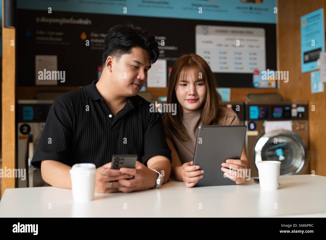 Giovane coppia asiatica fiduciosa nel negozio di lavanderia Foto Stock