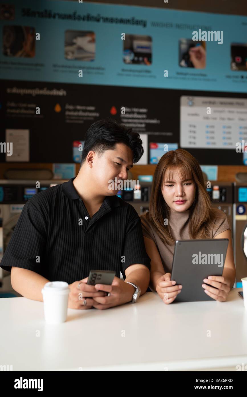 Giovane coppia asiatica fiduciosa nel negozio di lavanderia Foto Stock