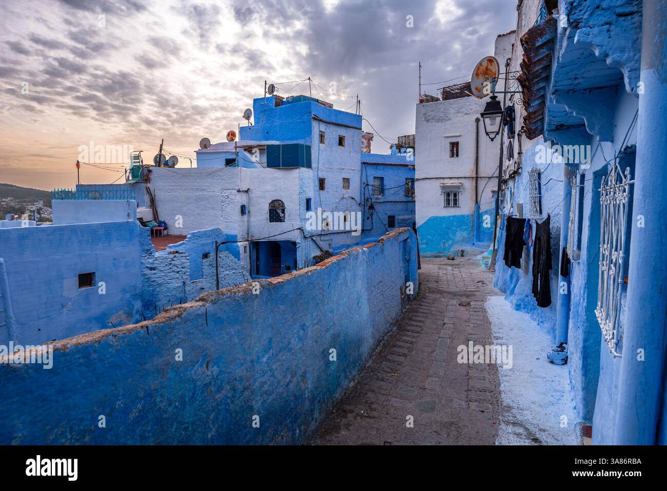 Una strada stretta di edifici dipinti di blu, piante in vaso e fascino rustico, Chefchaouen, Marocco Foto Stock
