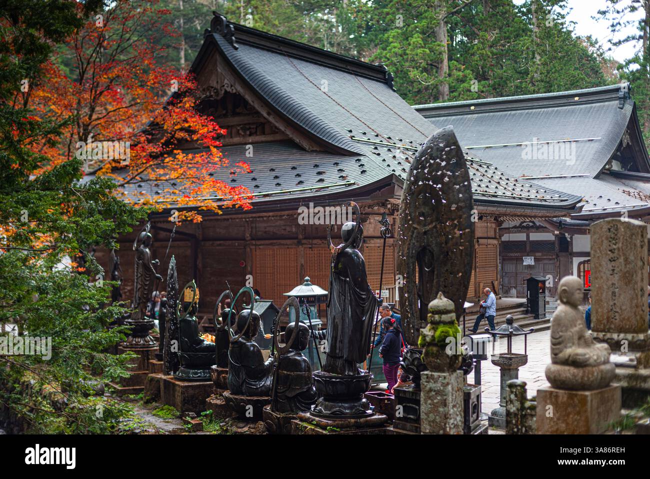 Un tradizionale tempio giapponese circondato da lapidi e vibrante fogliame autunnale nei terreni sacri di Koyasan (Monte Koya), Honshu, Giappone Foto Stock