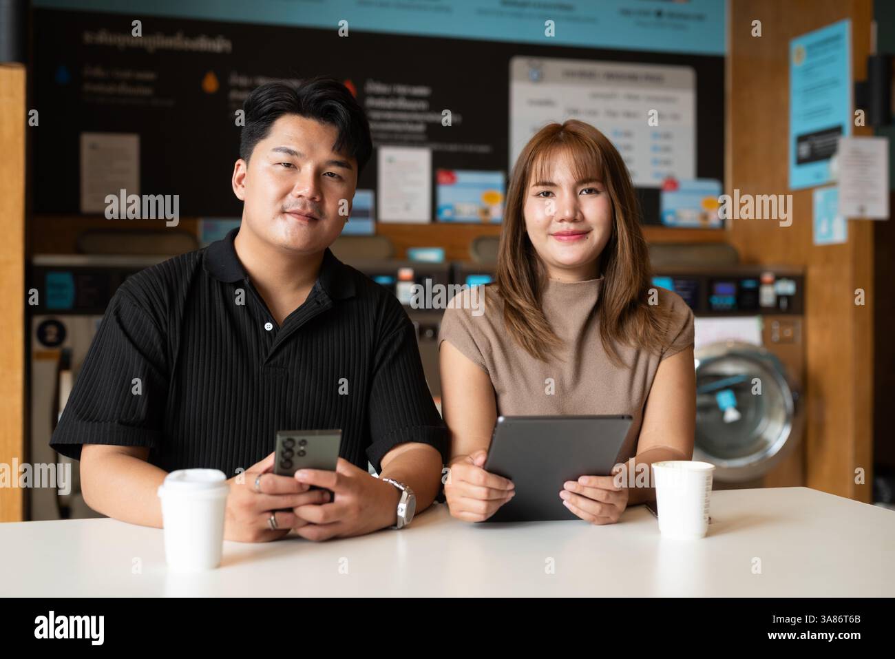 Giovane coppia asiatica fiduciosa nel negozio di lavanderia Foto Stock