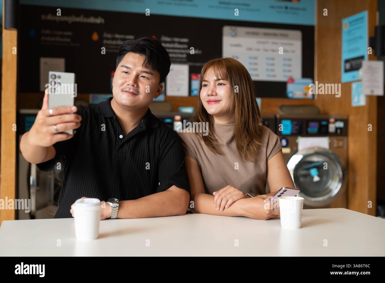 Giovane coppia asiatica fiduciosa nel negozio di lavanderia Foto Stock