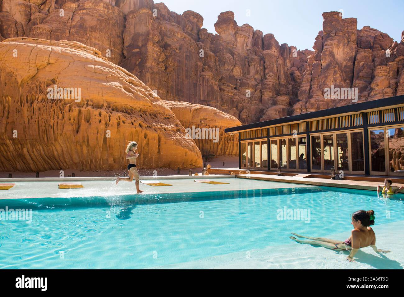 Donna che corre a bordo della piscina del nostro Habitas Alula, resort in un'antica oasi nel canyon del deserto, Ashar Valley, Medina Province, Arabia Saudita Foto Stock