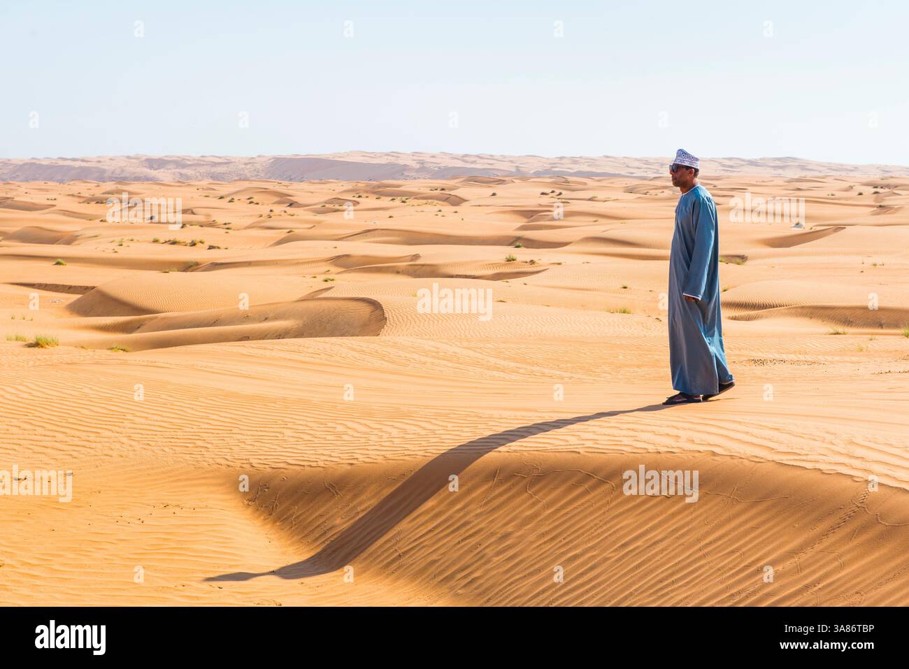 Uomo in piedi su una duna a Wahiba Sands (Sharqiya Sands), regione del deserto nel Sultanato dell'Oman Foto Stock