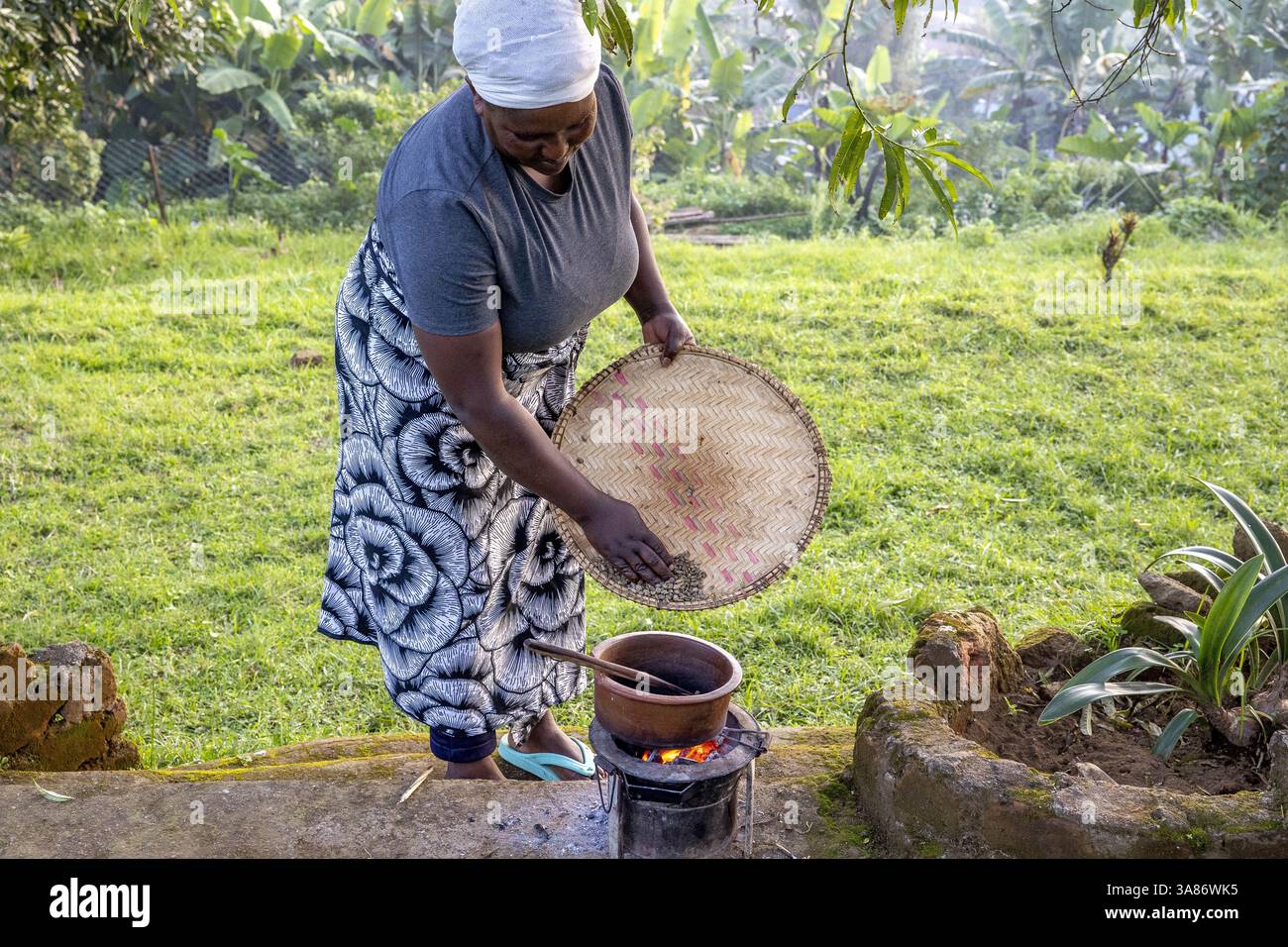 Donna che tosta chicchi di caffè nel villaggio di Ngiresi, Tanzania Foto Stock