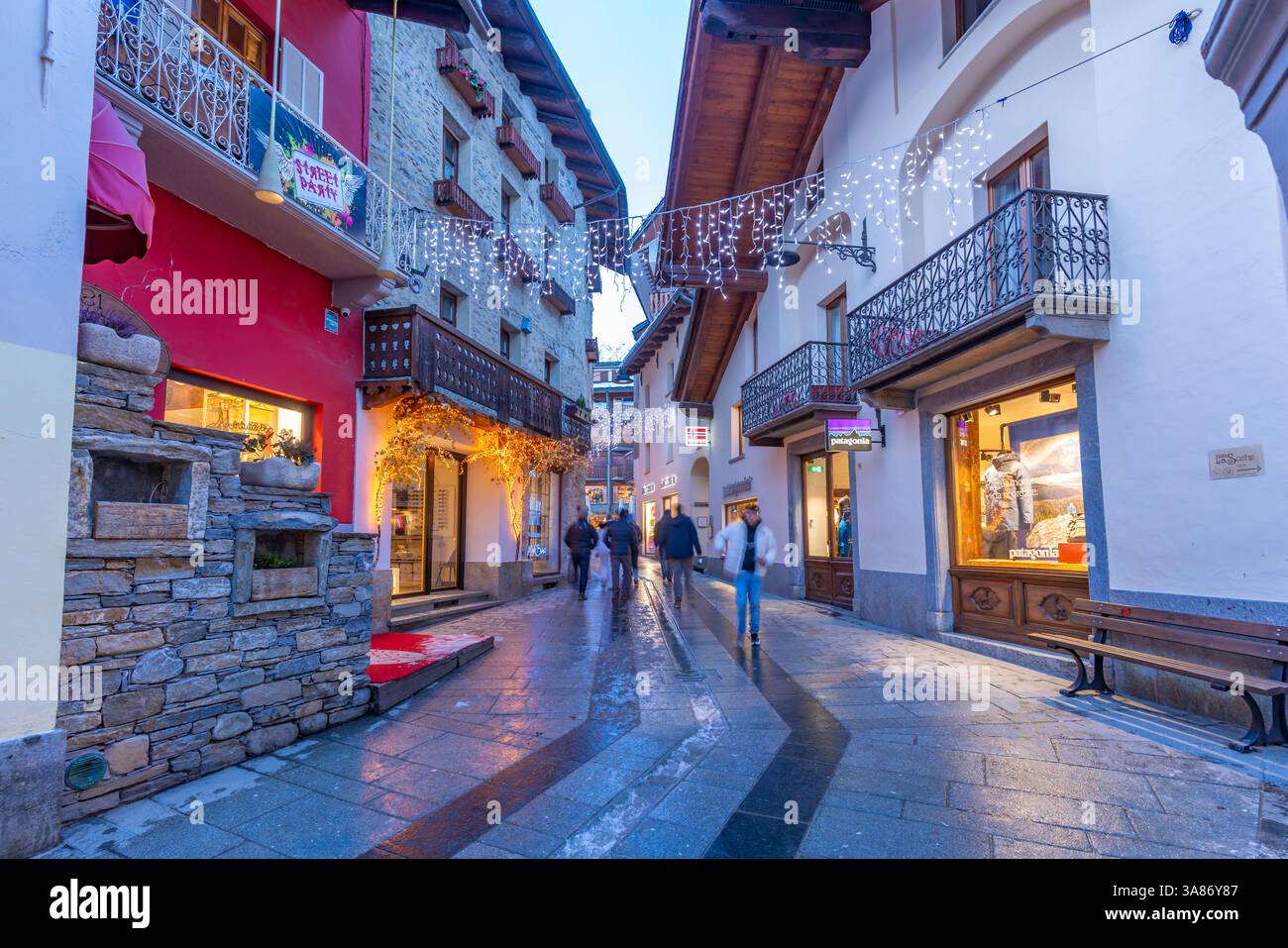 Vista dei negozi del centro città sulla neve a Courmayeur al crepuscolo durante il Natale, Courmayeur, Valle d'Aosta, Alpi italiane, Italia Foto Stock