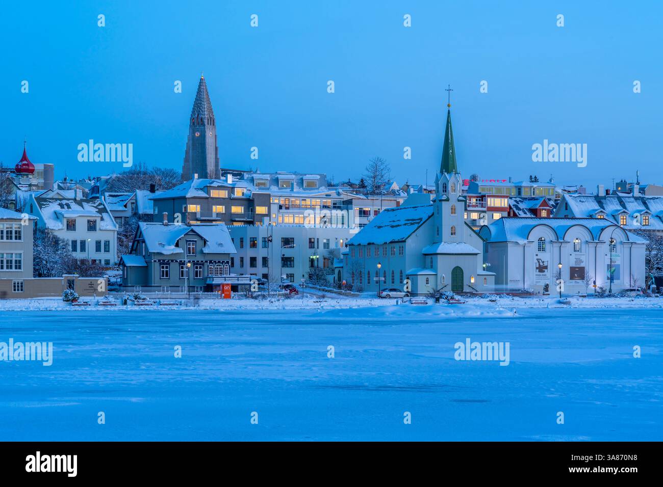 Vista della chiesa di Hallgrimskirkja e dello skyline della città di Reykjavik dal lago Tjornin al tramonto in inverno, Reykjavik, Islanda Foto Stock