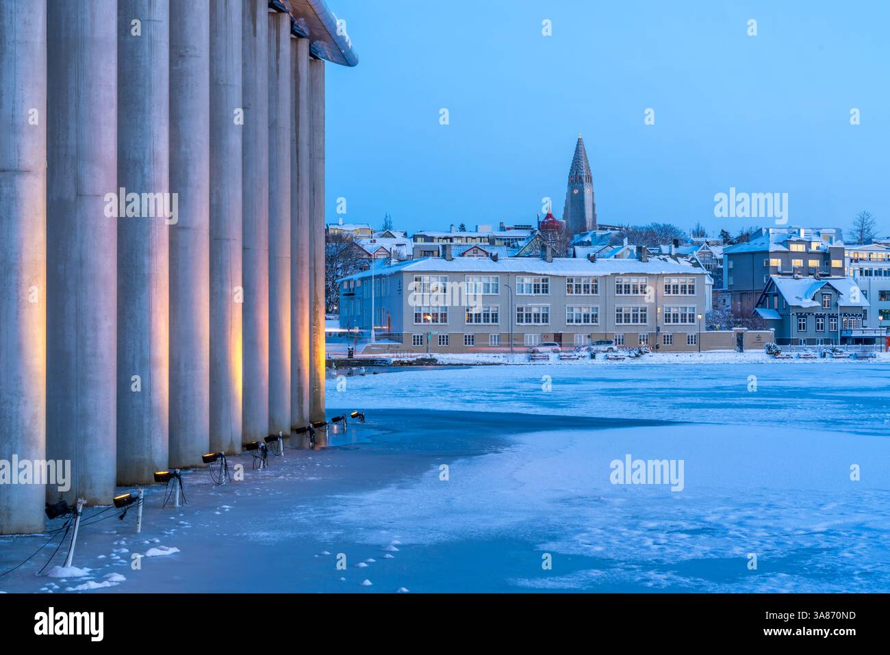 Vista dell'edificio in miniatura islandese e della chiesa di Reykjavik Hallgrimskirkja dal lago Tjornin al crepuscolo in inverno, Reykjavik, Islanda Foto Stock