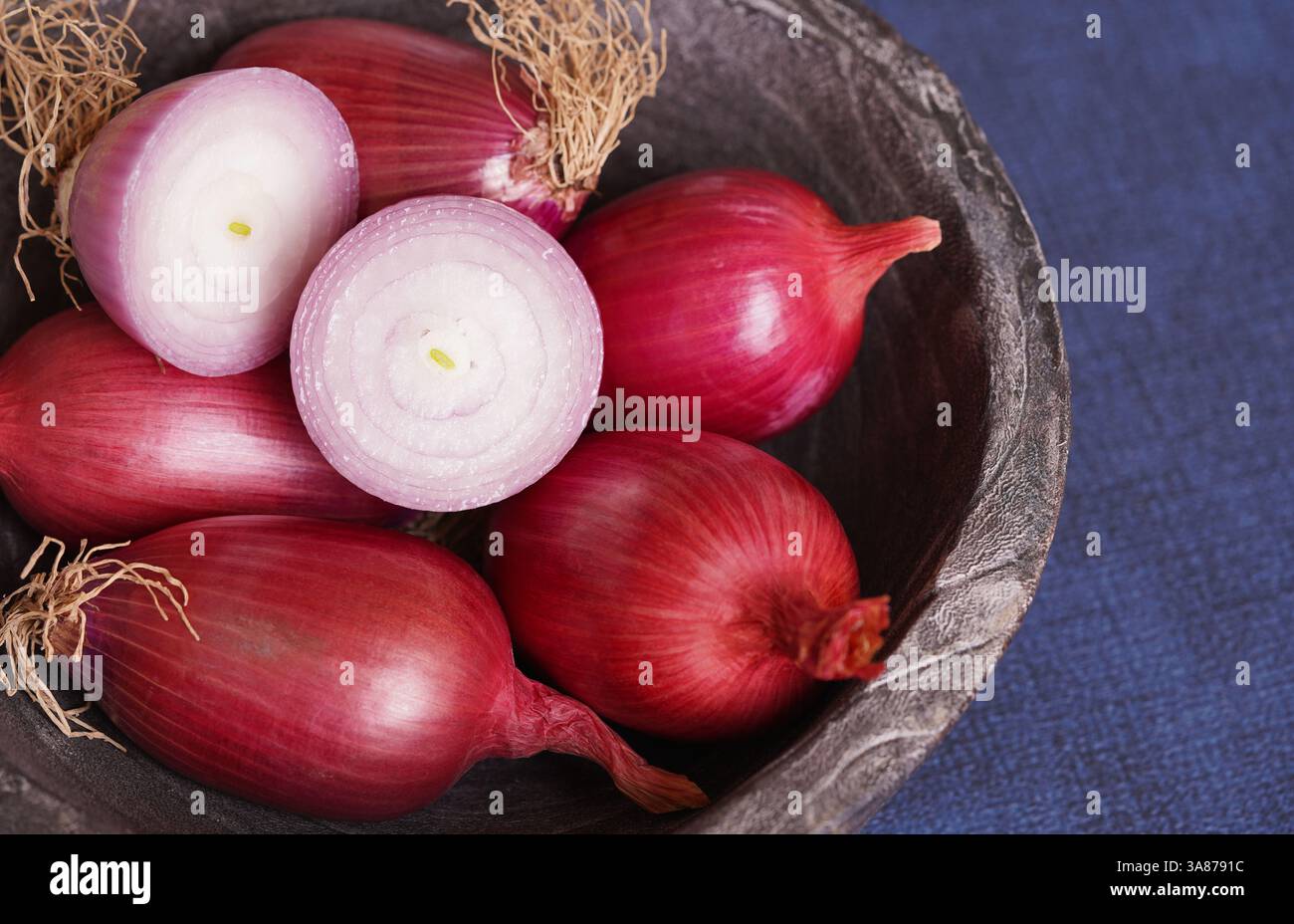Primo piano di cipolle rosse di Tropea su un recipiente di legno e una cipolla rossa a fette sopra. Foto Stock