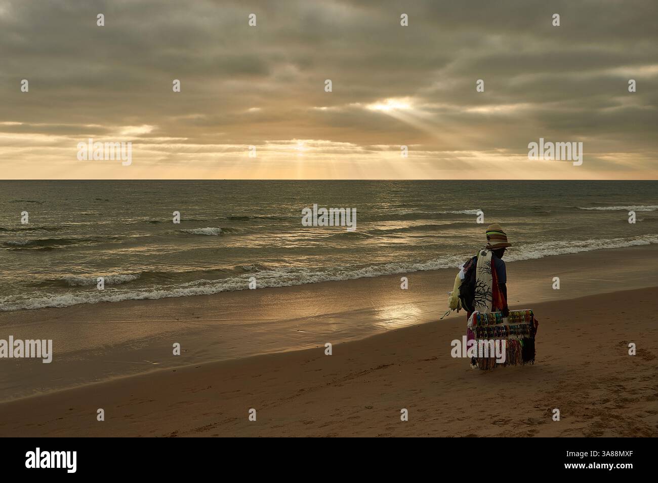 Un venditore ambulante che vende merci sulla spiaggia di El Palmar, Cádiz, Spagna, che offre prodotti locali sotto il sole in un'atmosfera costiera rilassata Foto Stock