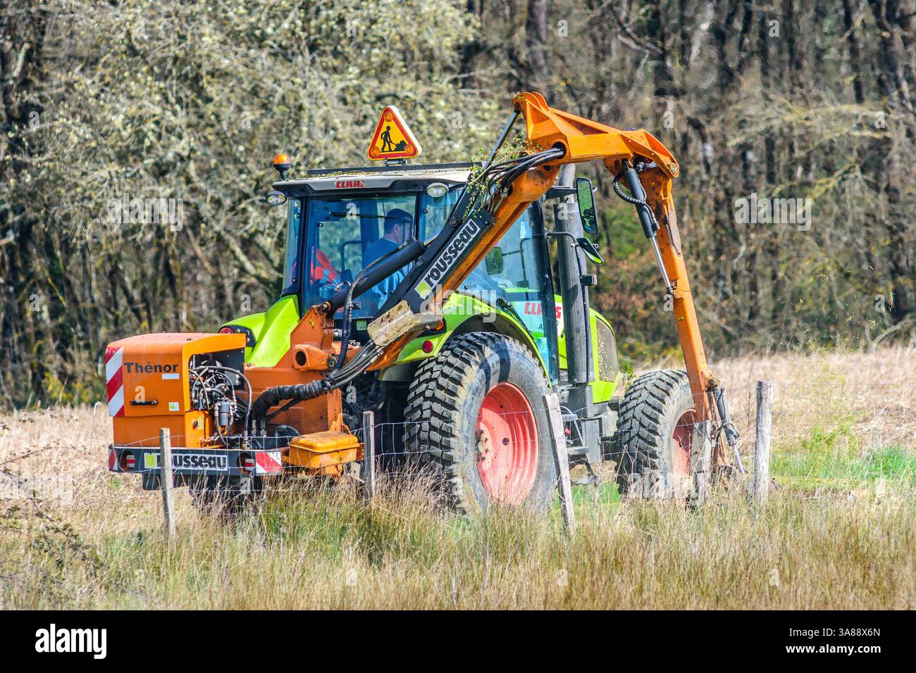 Trattore Claas 410 Arion con rasaerba Thénor Rousseau che taglia erba al limite della corsia di campagna - sud-Touraine, Francia. Foto Stock