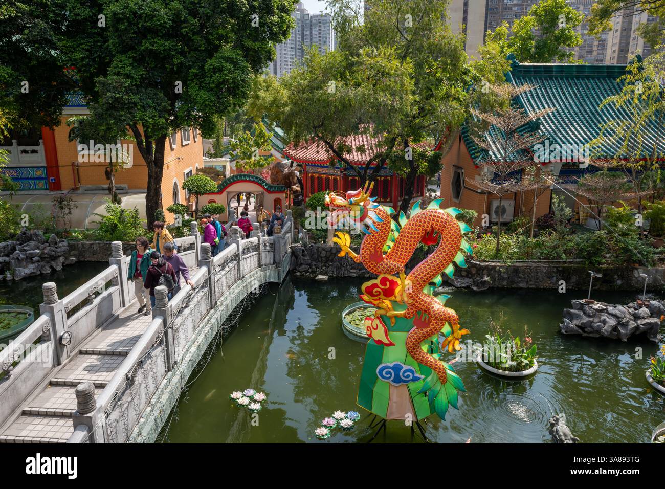 Hong Kong. Cina- 02.24.2025. Vista ad alto angolo del tradizionale ponte in pietra di stile cinese e installazione di draghi sullo stagno di Good Wish Garden Foto Stock