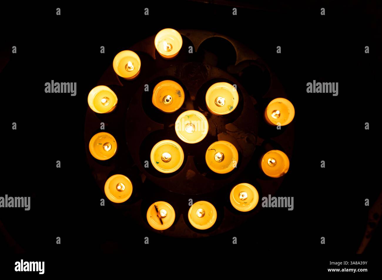 Candele in cerchio che si illuminano al buio all'interno di una chiesa, vista dall'alto Foto Stock