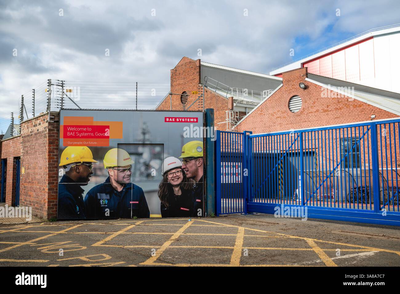 Cancelli del cantiere BAE Systems di Govan, Glasgow, Scozia, con segnaletica promozionale ed edifici industriali. Foto Stock