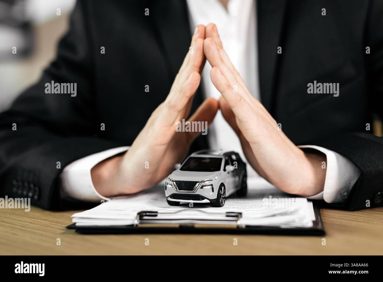 Le mani di uno spacciatore su un'auto giocattolo e il contratto. Lo scopo di assicurare, leasing o acquisto di un'auto nuova. Foto Stock