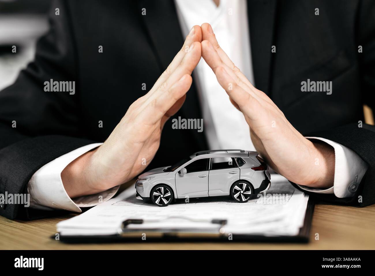 Le mani di uno spacciatore su un'auto giocattolo e il contratto. Lo scopo di assicurare, leasing o acquisto di un'auto nuova. Foto Stock