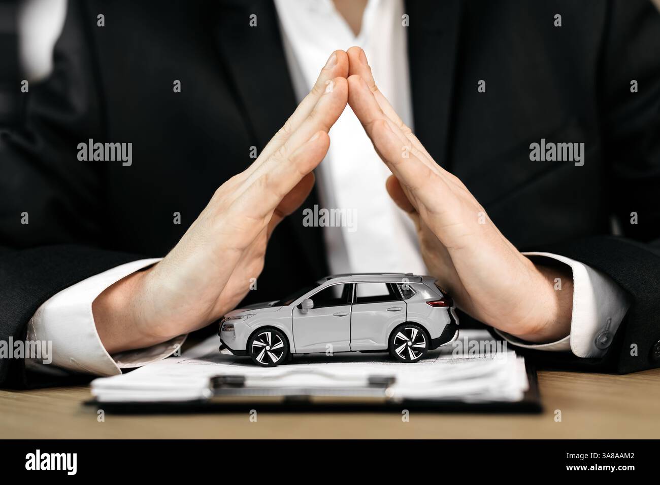 Le mani di uno spacciatore su un'auto giocattolo e il contratto. Lo scopo di assicurare, leasing o acquisto di un'auto nuova. Foto Stock