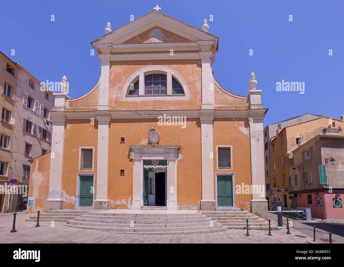 Ajaccio, Corsica, Francia 8 luglio 2024: Facciata anteriore della cattedrale di Santa Maria Assunta di colore marrone beige sotto il cielo blu. Shamrock Irish Pub come vicino Foto Stock