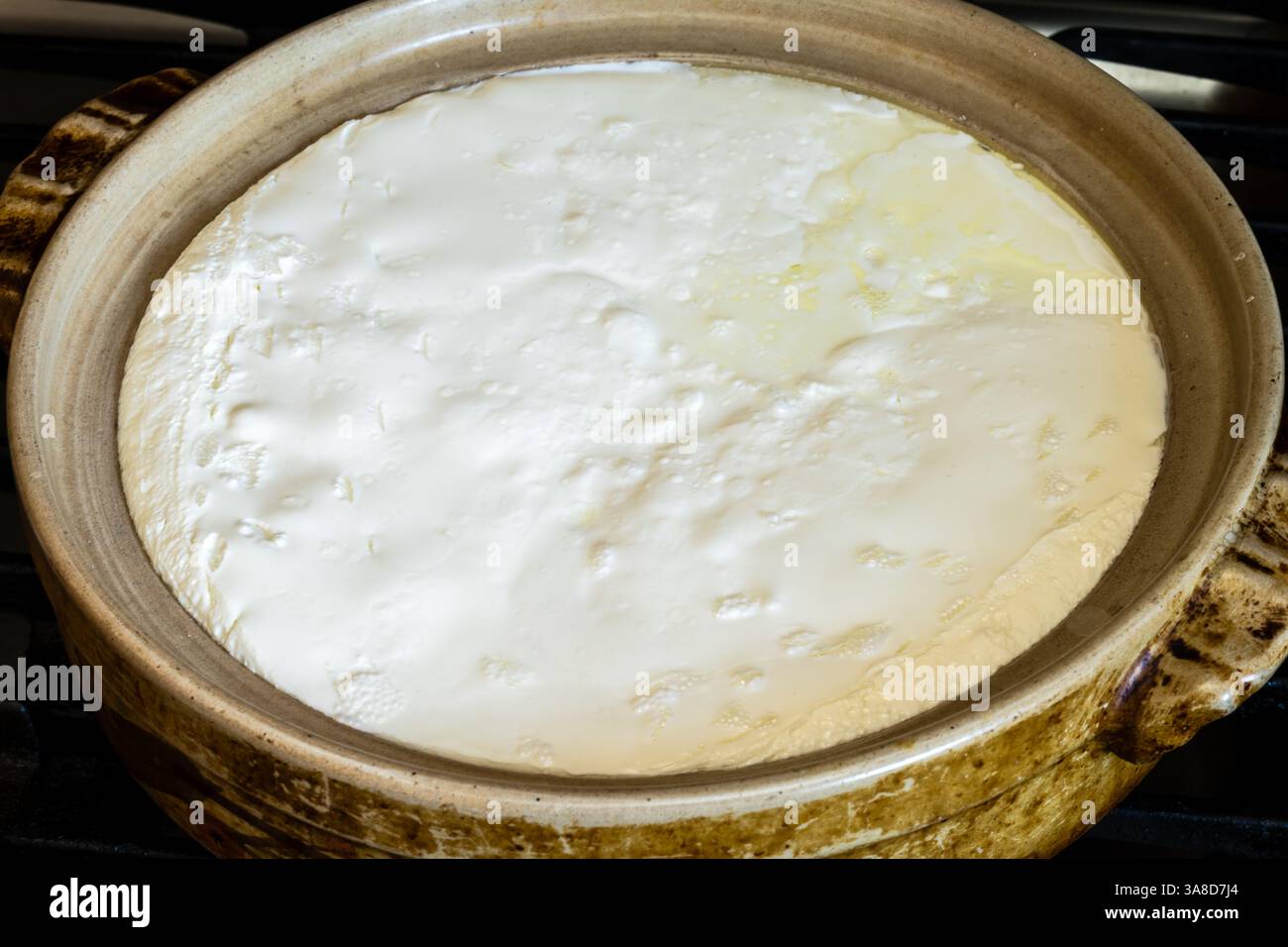 Il latte fermentato con microrganismo di coltura acida riscaldato per la coagulazione in pentola di sabbia è pronto per la separazione del siero di latte e del formaggio Foto Stock